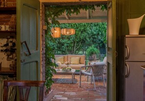 An open doorway leading to a cozy outdoor seating area with a brick floor, a sofa, and a chair. - A Peaceful 3-Bedrooms Oasis In Orentano (Orentano)