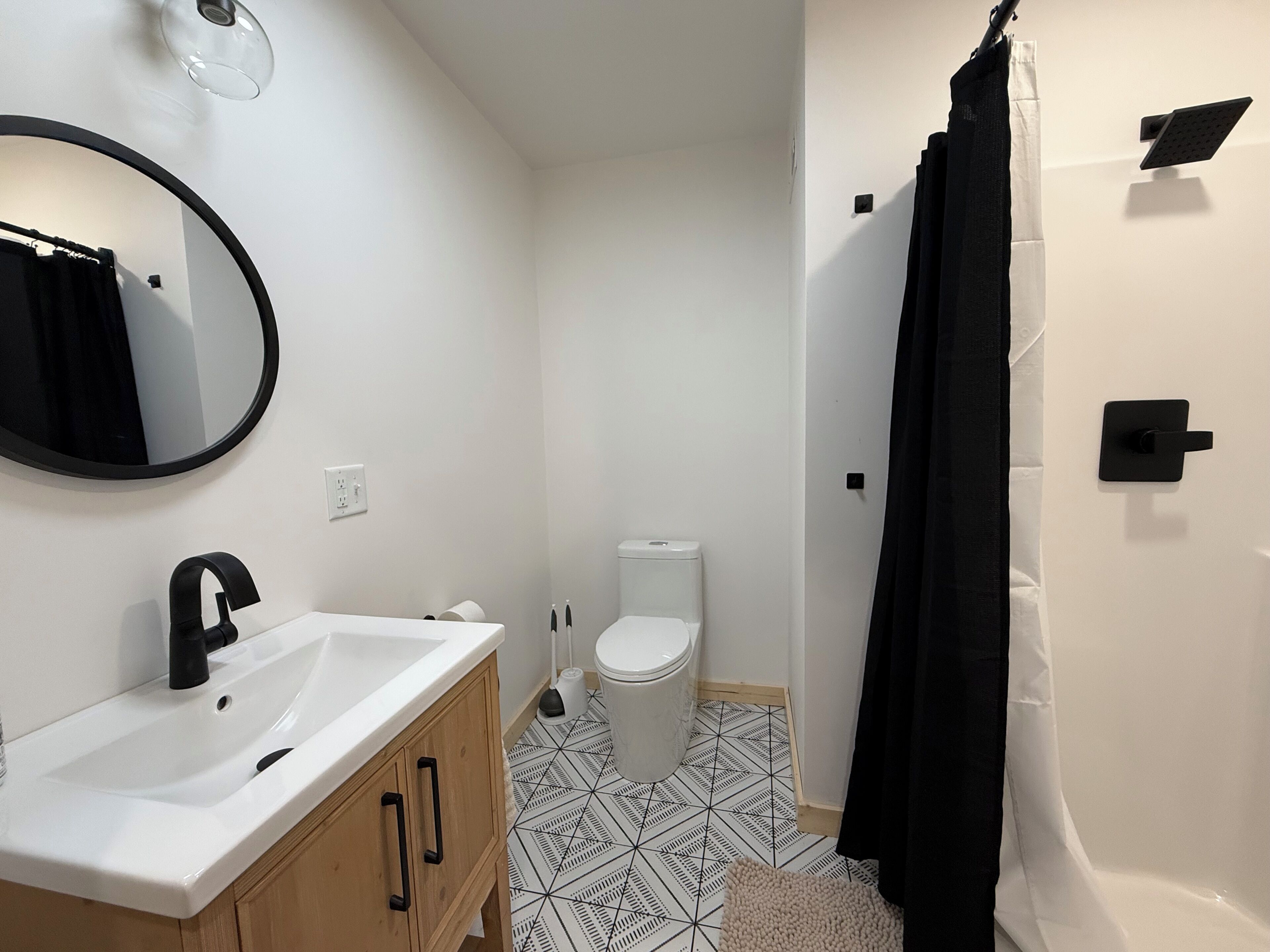 A bathroom with a white sink, black faucet, a toilet, and a shower curtain.