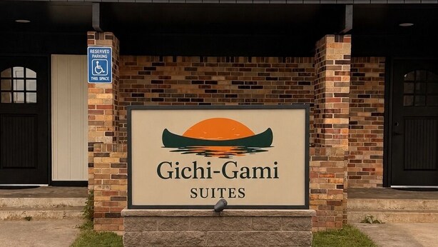 En skylt för Gichi-Gami Suites med en bild av en kanot och en solnedgång.