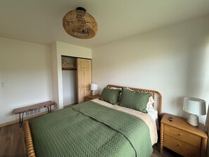 Un dormitorio con cama, mesita de noche, lámpara y un banco de madera.