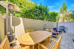 A patio with a round wooden table and chairs, a barbecue grill, and a wall-mounted water fountain. - Great 4 Families, Walk 2 Beach and Bay W/Parking! (Newport Beach)