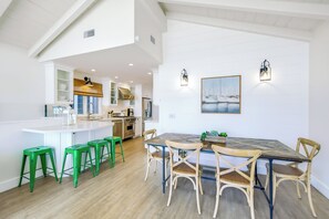 A spacious kitchen with a central island, green bar stools, and a dining table with chairs. - Great 4 Families, Walk 2 Beach and Bay W/Parking! (Newport Beach)