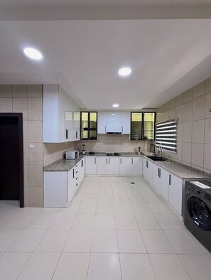 A modern kitchen with white cabinets, a built-in washing machine, and a granite countertop.