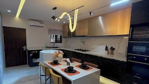 Uma cozinha moderna com ilha central, iluminação embutida e forno integrado.