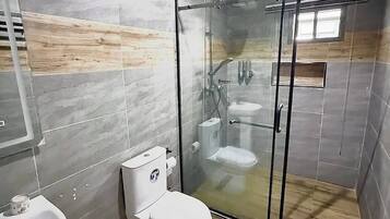 A modern bathroom with a glass-enclosed shower, a toilet, and a sink.