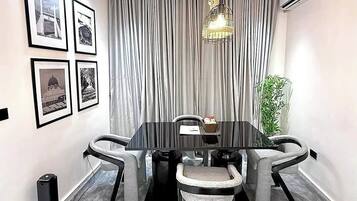 A modern conference room with a black table, grey upholstered chairs, a chandelier, and framed pictures on the wall.