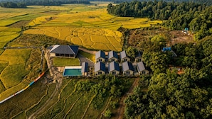 An aerial view of a property with terraced fields, a swimming pool, and multiple houses with a central building.