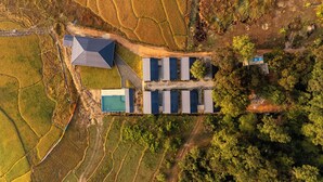 An aerial view of a property with a large building, solar panels, and terraced fields.