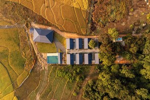 An aerial view of a property with a large building, solar panels, and terraced fields.