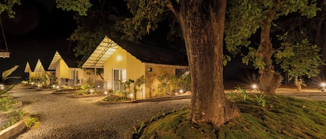 A building with a sloped roof and a large tree in front.