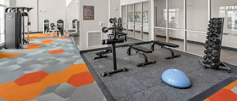 A gym with exercise equipment, a blue exercise ball, and a wall with a 'GET FIT' sign.