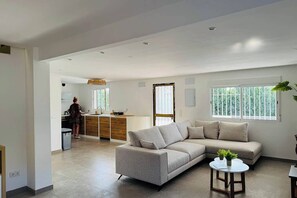 A modern living room with a sofa, a small table, and a kitchen area in the background. - Villa Perfecta: A 5-bedroom villa with a pool, just 30 minutes from Valencia! (Llíria)