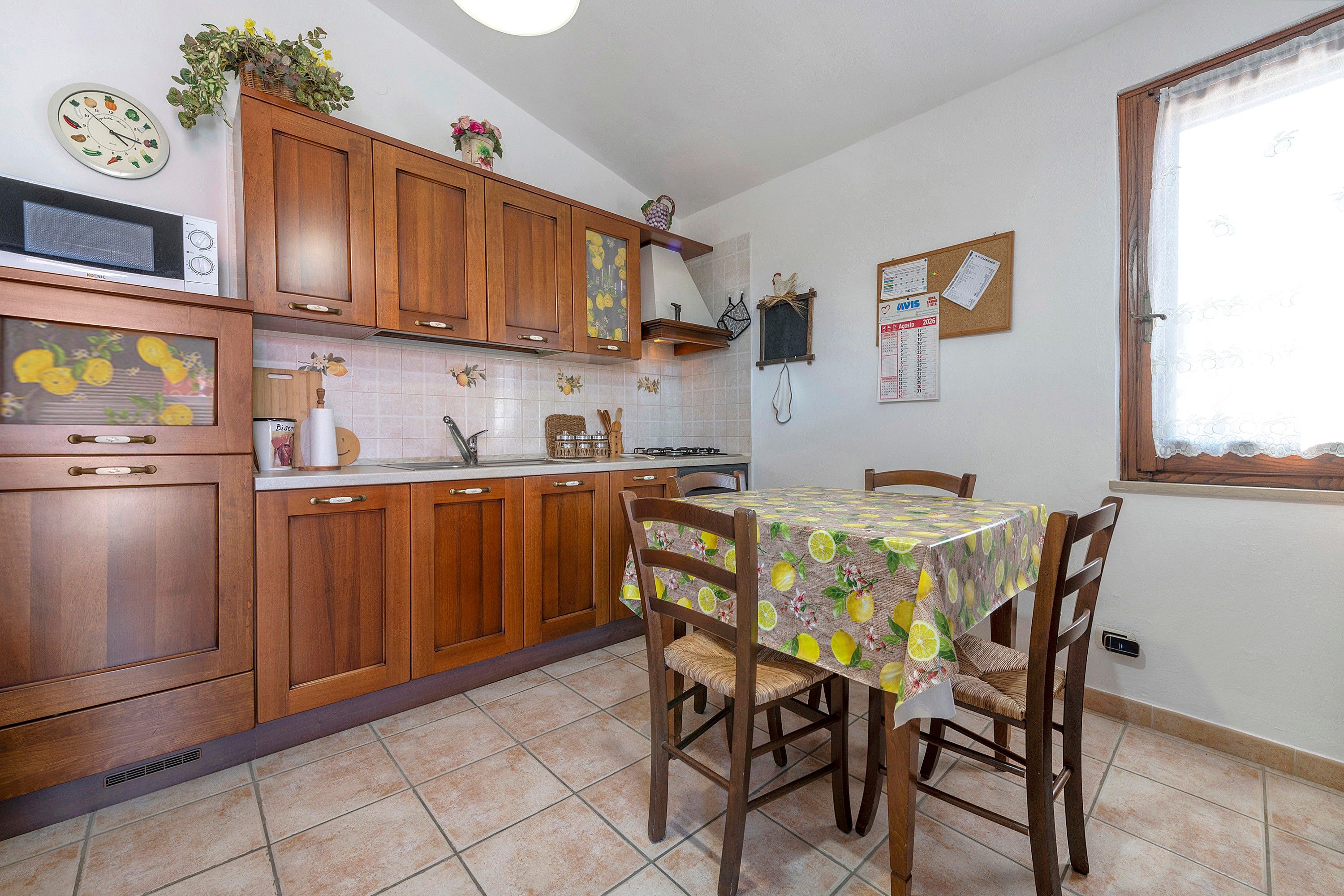 Une cuisine avec des meubles de rangement en bois, un four à micro-ondes et une table à manger avec des chaises.