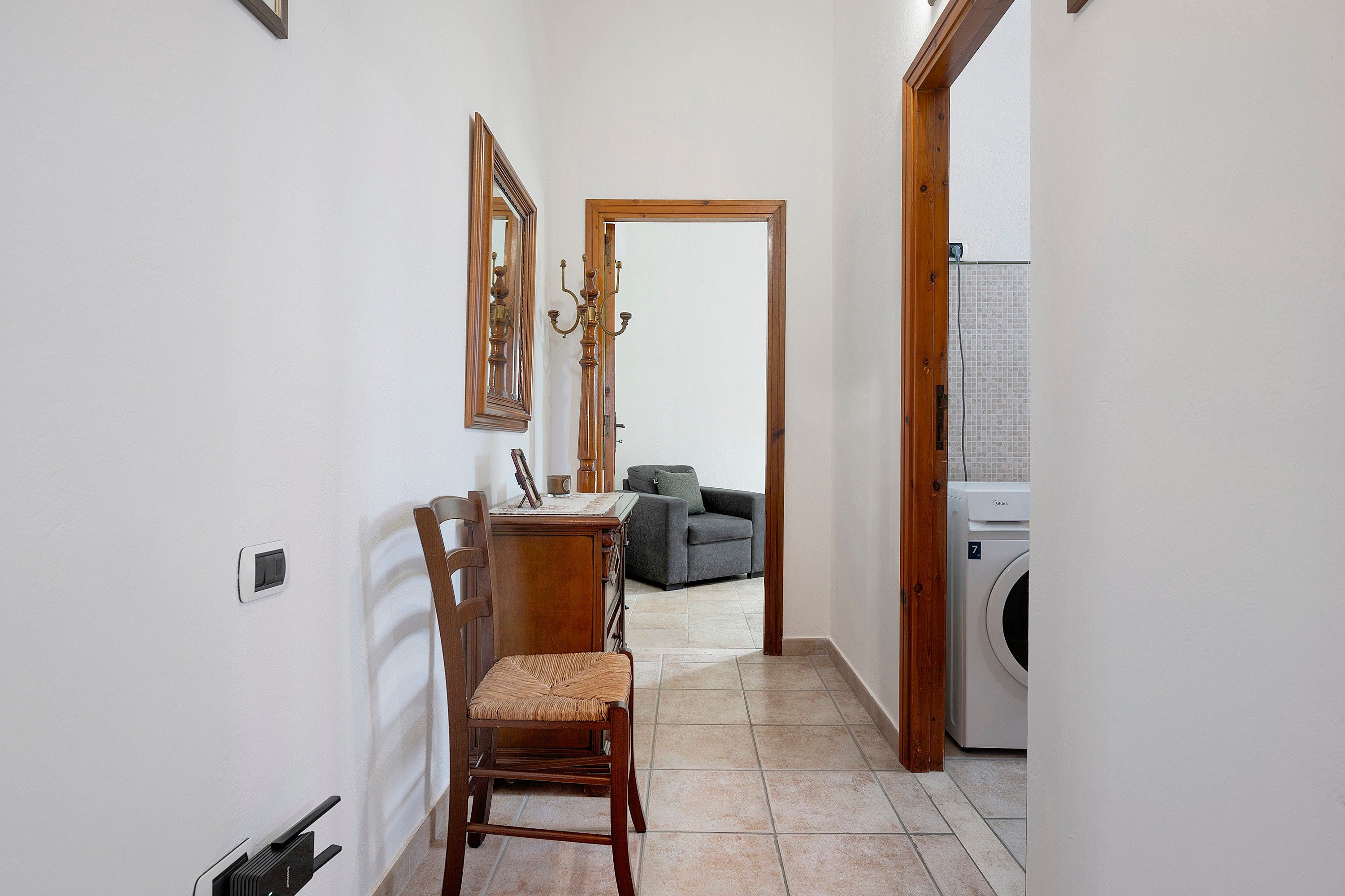 Un couloir étroit comprenant un coin repas, un canapé et un lave-linge.