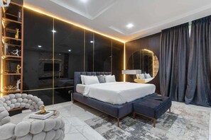 A modern bedroom with a large bed, a built-in wardrobe, and a round mirror. - Exclusive Homes By Bomma  (Abuja)