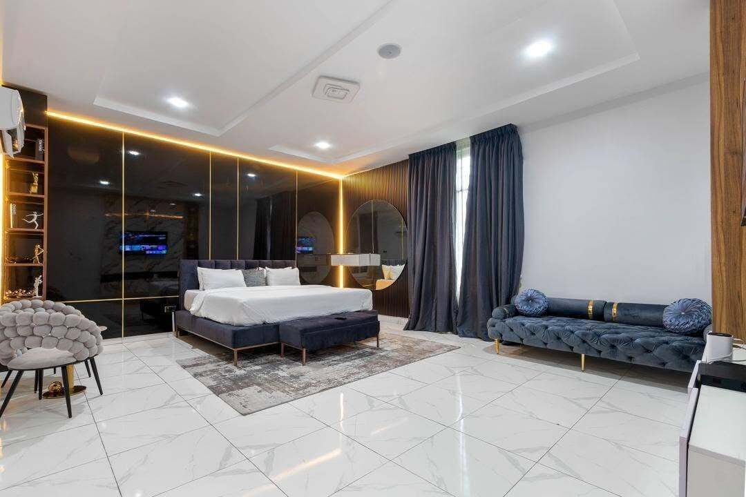 Un dormitorio moderno con una cama grande, un sofá, una silla y un televisor.