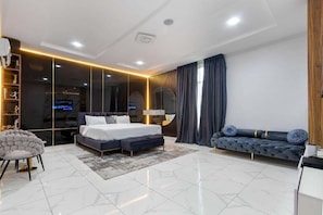 Un dormitorio moderno con una cama grande, un sofá, una silla y un televisor.