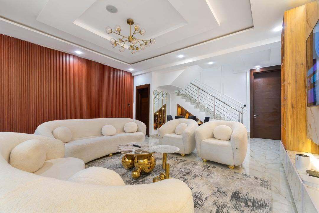 A modern living room with a sectional sofa, a coffee table, and a staircase leading to an upper level.