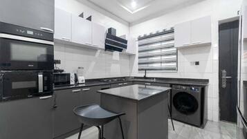 Une cuisine moderne dotée d’un îlot central, d’appareils électroménagers intégrés et d’un lave-linge.