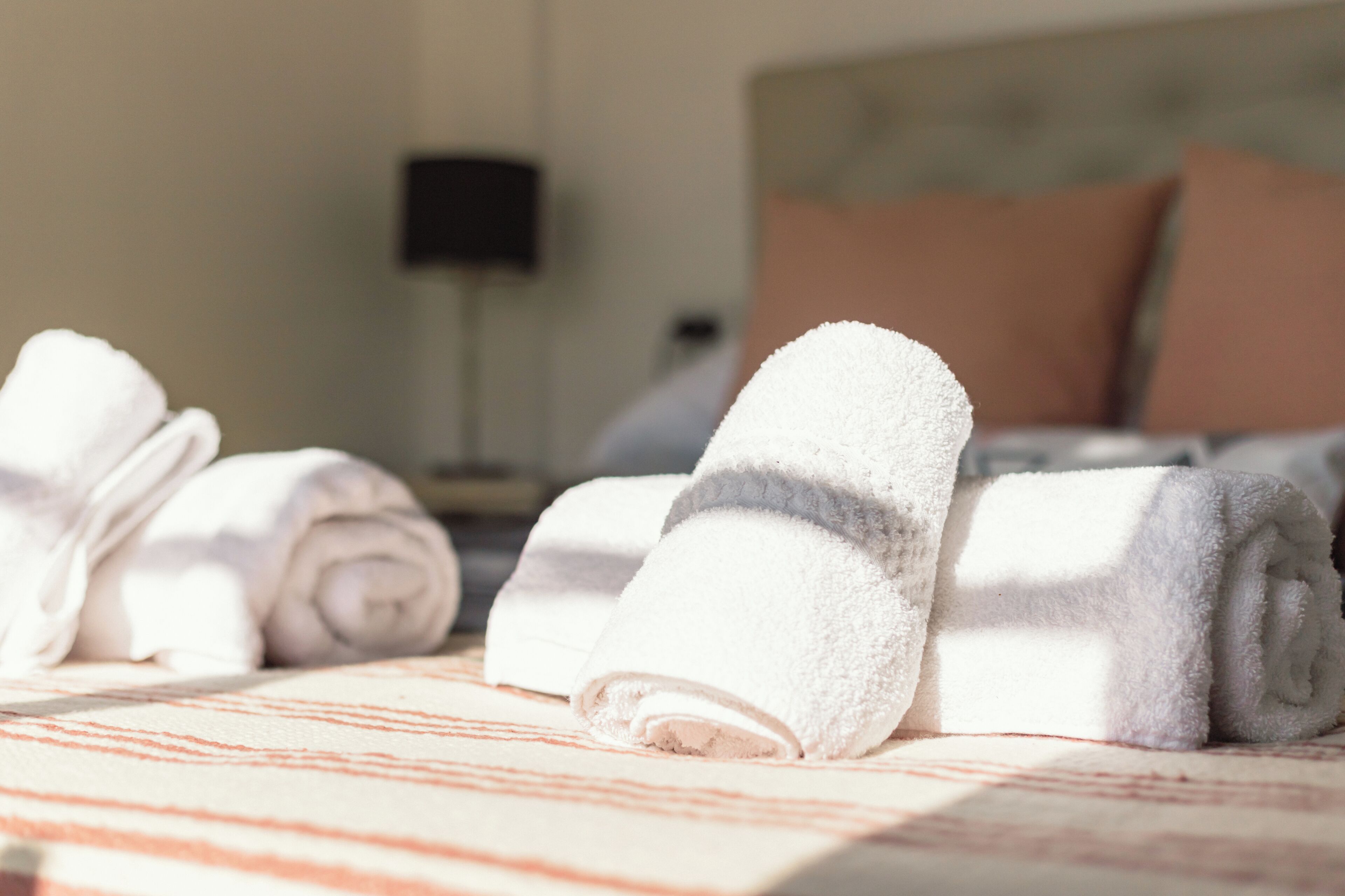 A neatly made bed with rolled white towels and a striped blanket.