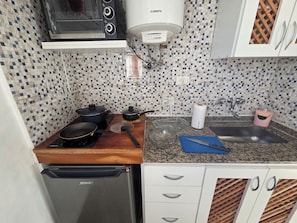 Eine Küche mit Mikrowelle, Herd, Wasserkocher und Kühlschrank.