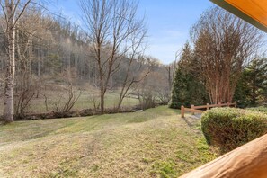 A view of a grassy area with trees and a wooden fence. - Cabin beside Shepherd Creek with Hot Tub and Fire Pit - A World’s Inn Property (Bryson City)