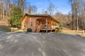 A wooden cabin with a porch, a staircase, and a small front yard. - Cabin beside Shepherd Creek with Hot Tub and Fire Pit - A World’s Inn Property (Bryson City)