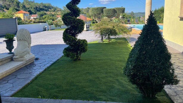Um jardim com paisagismo, apresentando uma árvore espiral, uma estátua e uma piscina.