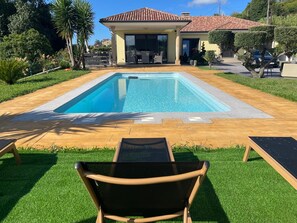 A swimming pool with a patio area, a covered seating area, and a view of a residential building.