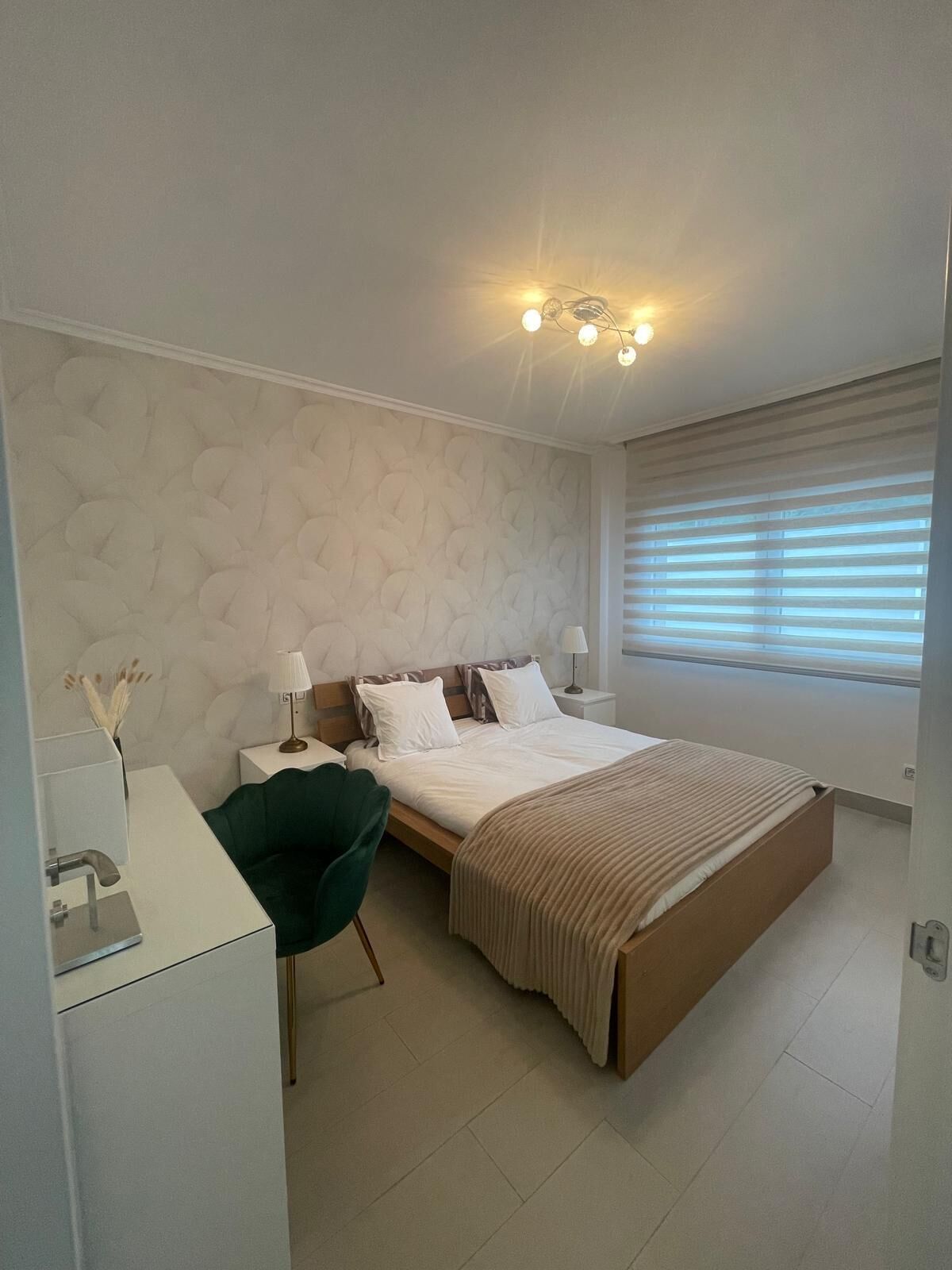 A modern bedroom with a bed, bedside tables, a desk, and a chair.