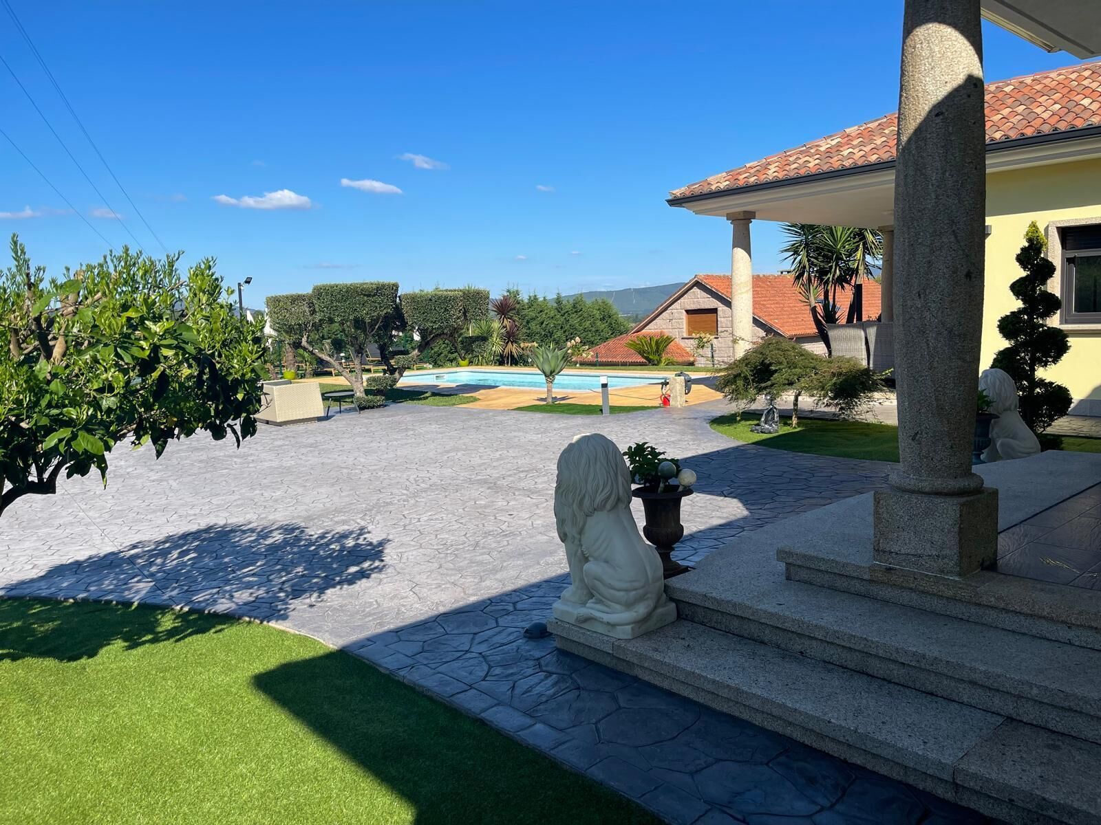 A courtyard with a pool, a statue, and a stone staircase leading to a building.