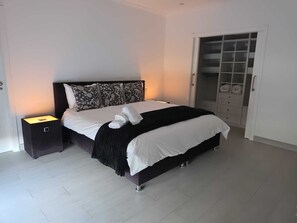 A modern bedroom with a bed, bedside tables, and a wardrobe.