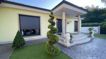 A residential property with a paved driveway, a covered entrance, and a well-maintained lawn.