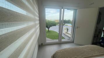 Een slaapkamer met een bed, een schuifdeur die uitkomt op een tuin en uitzicht op een zwembad.
