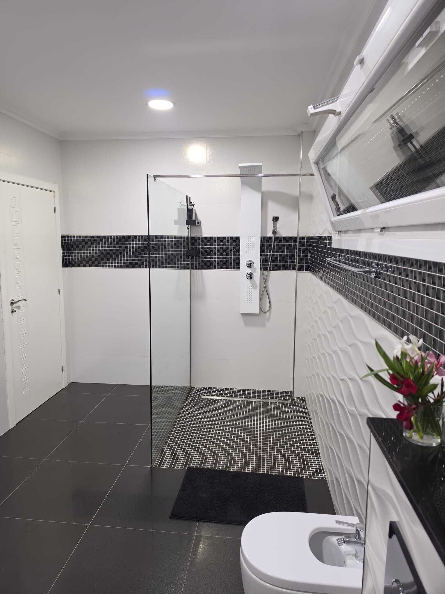 Een moderne badkamer met een douchecabine van glas, een wit toilet en een zwart-wit betegelde vloer.