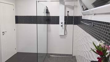 Een moderne badkamer met een douchecabine van glas, een wit toilet en een zwart-wit betegelde vloer.