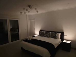 Ein Schlafzimmer mit einem Bett, Nachttischen, einer Deckenleuchte und einer Schiebetür.