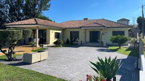 Uma casa de dois andares com telhado de telhas, entrada pavimentada e gramado bem cuidado.