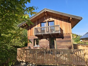 Eine Holzhütte mit Balkon, Terrasse und Fenster.
