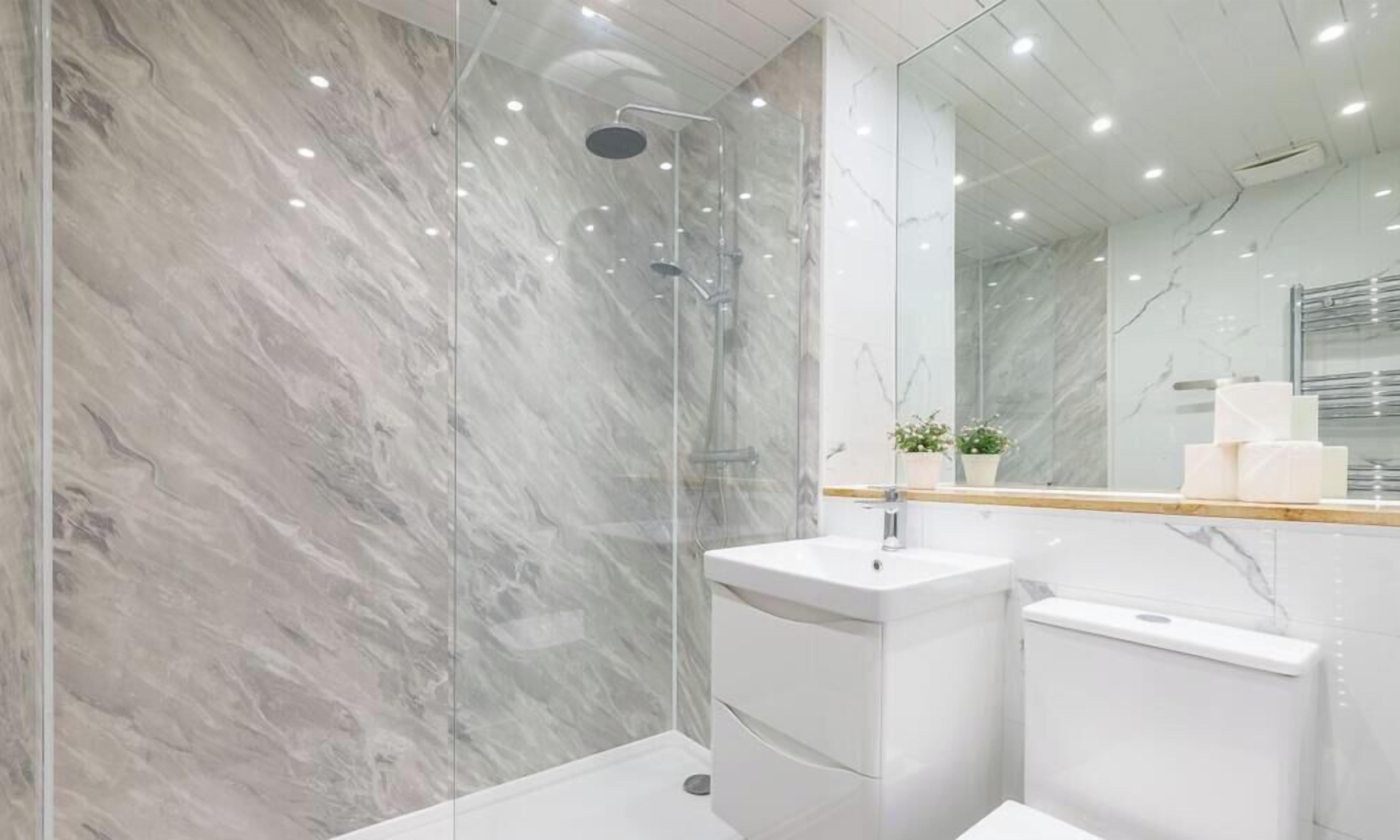 Ein modernes Badezimmer mit einer gläsernen Dusche, einem weißen Waschbecken und einer Wand mit Marmorfliesen.