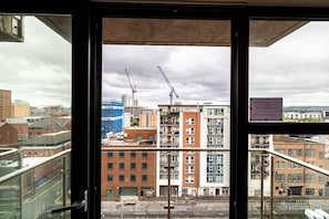A view from a window overlooking a cityscape with buildings, including a construction site with cranes. - Belfast Quarters 8th Floor Gem! (Belfast)