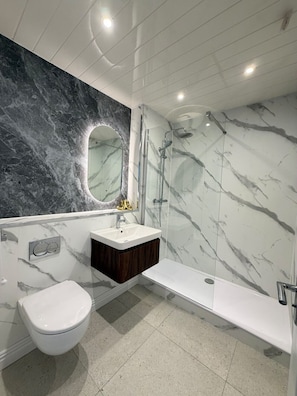 A modern bathroom with a marble vanity, a toilet, and a glass-enclosed shower. - Belfast Quarters: Riverside (Belfast)