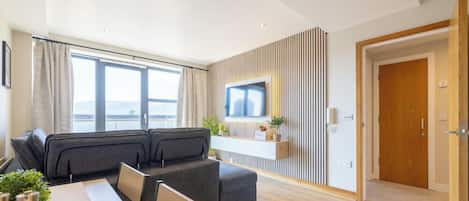 A modern living room with a sofa, a TV mounted on a wall, and a wooden door.