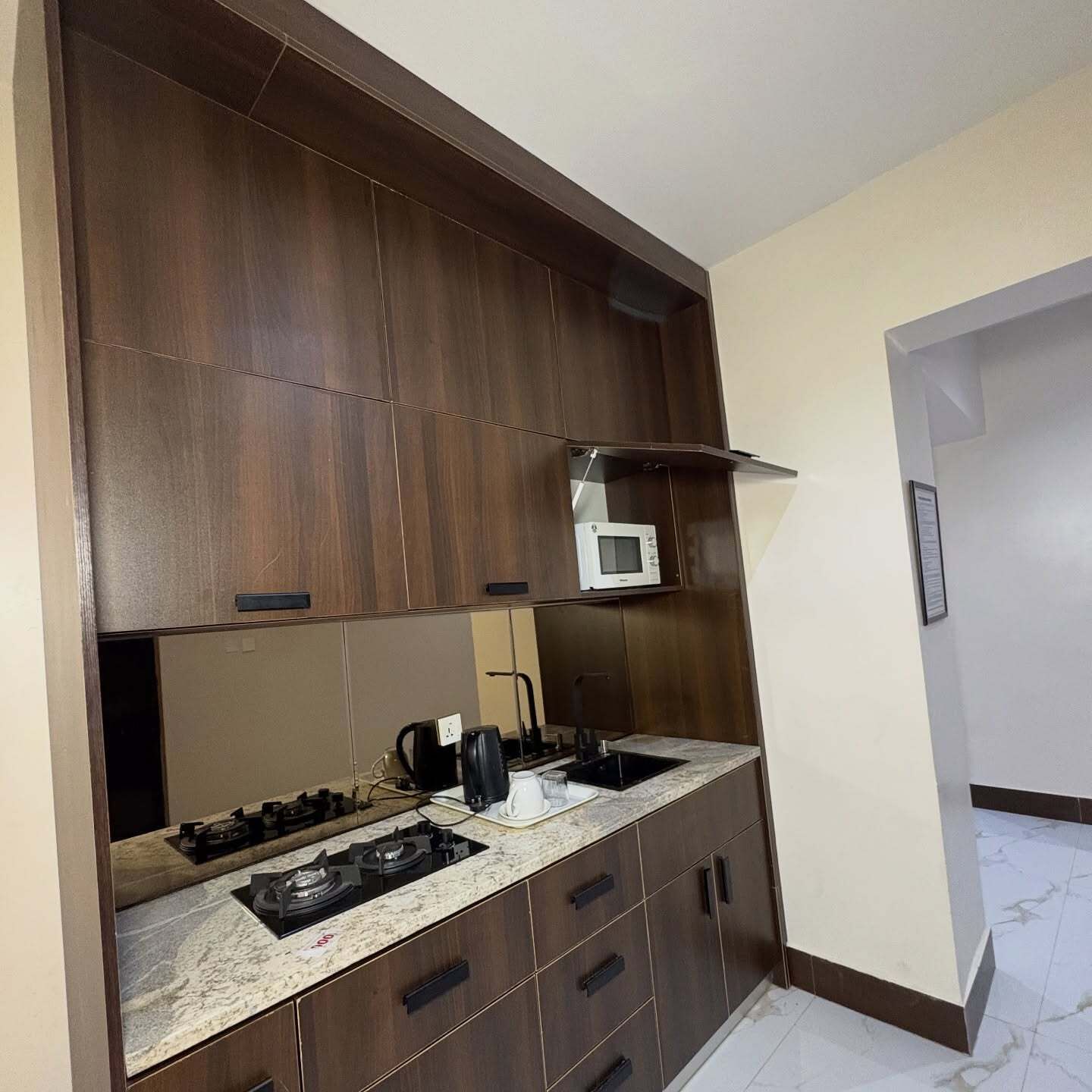 A compact kitchen with dark wood cabinets, a built-in microwave, a gas stove, and a coffee maker.