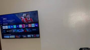 A flat-screen TV mounted on a wall displaying a sports channel with various app icons.