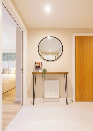 Ein Zimmer mit einem runden Spiegel an der Wand, einer Holztür, einem weißen Heizkörper und einem Bett mit einem gemusterten Kopfteil.