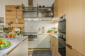 A modern kitchen with a built-in oven, a stainless steel range hood, and a marble countertop. - Villa Bertolli in Lucca (Lucca)