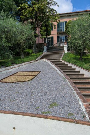 A pathway leading to a building with a staircase and a large tree. - Villa Bertolli in Lucca (Lucca)