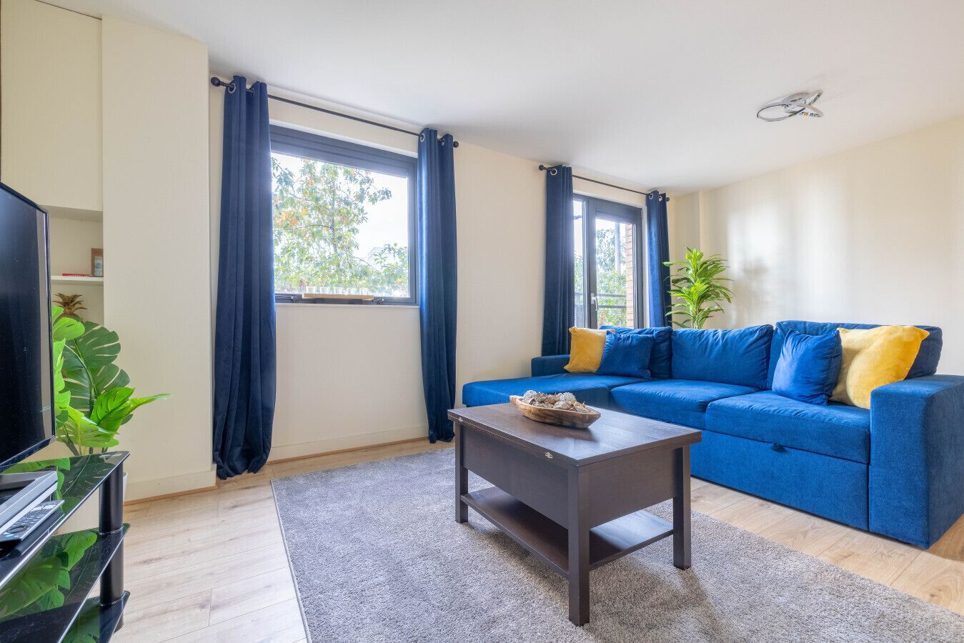 A living room with a blue sofa, a coffee table, and a TV on a stand.