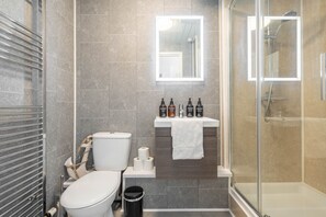 Un bany modern amb vàter, bidet i plat de dutxa.